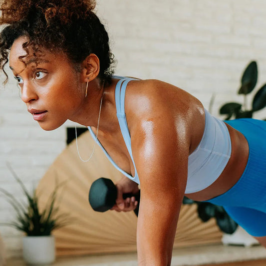 Woman performing push-up with dumbbell during strength training workout, illustrating fitness and calcium support for weightlifters.