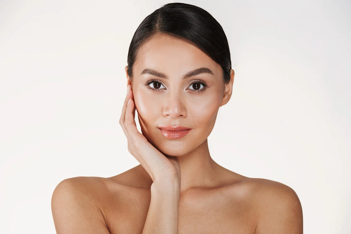 Woman with smooth skin touching her face against a white background.